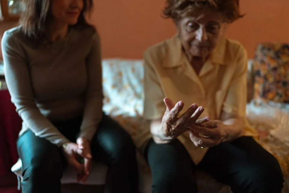 An older woman sharing a conversation with a companion at home